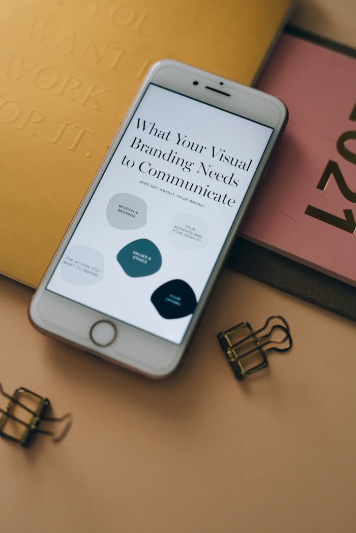 iPhone displaying visual branding needs with office stationery on desk.
